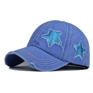 Dettaglio della stella di paillettes e strappi usurati sul berretto di jeans lavato blu