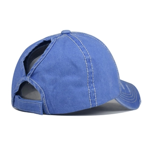 Dettaglio del cappello in cotone blu slavato con foro per coda di cavallo e cinturino