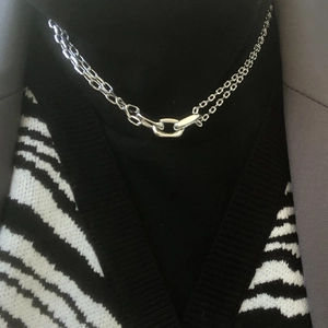 Close-up of double-layer silver chain necklace with oval rings worn over black clothing