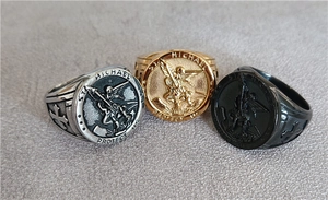 Detailed view of Saint Michael signet rings in silver, gold, and black stainless steel