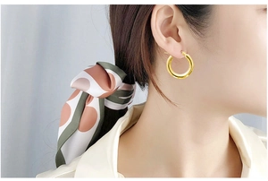 Close-up of chunky 18k gold plated stainless steel hoop earrings worn by a model