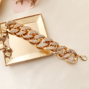 Dettaglio di una collana a catena dorata con strass su un vassoio decorativo chic
