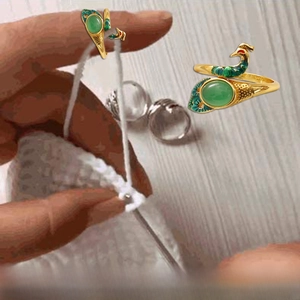 Detail of peacock crochet ring in gold finish with green gemstone for knitting