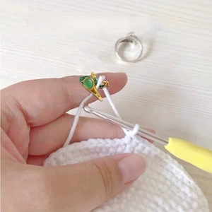 Adjustable peacock knitting ring for yarn tension and crochet guiding on light wood background