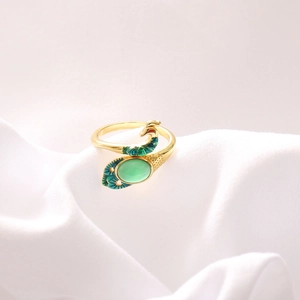 Macro detail of golden peacock ring with green gemstone and colorful enamel finish