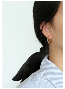 Close-up of golden hoop earrings with textured plaid pattern on the metal surface