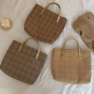 Detailed view of plaid canvas tote bags with leather handles and metal rivets