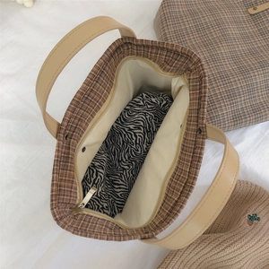 Detail view of the brown plaid tote bag interior with a zebra print zipper pocket