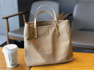 Close-up of yellow and blue plaid canvas tote with premium khaki leather handles