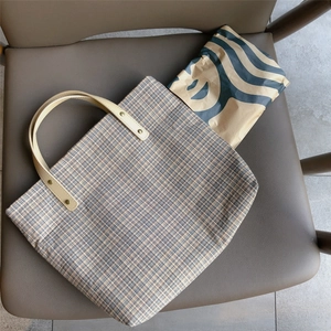 Close-up of vintage plaid tote bag with faux leather handle and gold rivet details