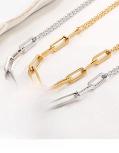 Close-up of gold and silver paperclip link necklaces on a beige textured surface