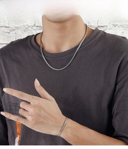 Detailed view of silver box chain necklace and bracelet set worn by a male model