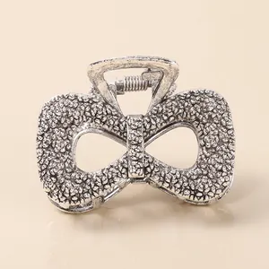 Macro shot of vintage matte silver alloy hair claw with bow shape and textured metallic surface