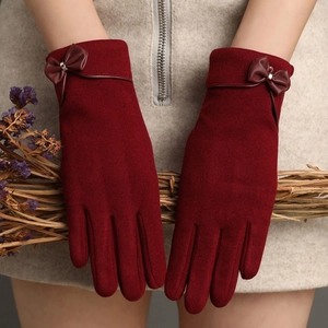 Detailed view of burgundy velvet gloves featuring a leather bow and warm winter texture