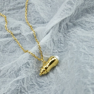 Collier biberon doré avec perle incrustée sur une chaîne minimaliste en acier
