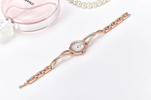 Detail of rose gold stainless steel watch with diamond-set dial and pearl accessories