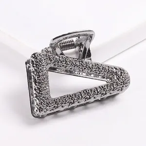 Detailed macro view of geometric hollow triangle hair claw with silver hammered texture
