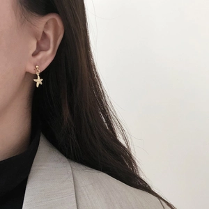 Elegant 14K gold plated starfish earrings worn with a beige blazer on white background