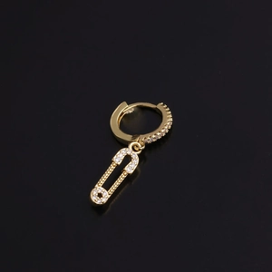 Macro shot of a gold safety pin earring featuring sparkling cubic zirconia on a black backdrop