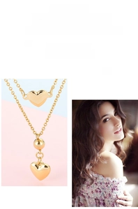 Close-up of double-layer gold necklace featuring minimalist smooth heart pendants