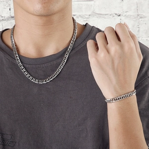 Silver stainless steel Cuban chain necklace and bracelet set shown on a male model