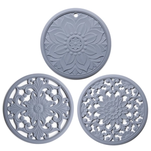 Detailed macro view of three grey heat-resistant silicone mats with floral carved patterns