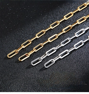 Detail of polished gold and silver paperclip chain links on black leather background