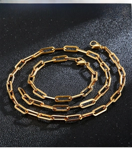 Detailed view of golden paperclip chain necklace and bracelet set with lobster clasp