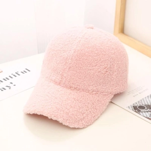 Close-up of pink fuzzy fleece baseball cap showing soft lamb wool texture on wooden base