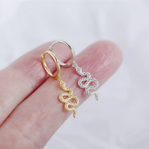 Close-up of irregular textured gold and silver snake earrings held by hand