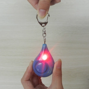 Close-up of blue teardrop personal alarm with glowing red LED light and keychain