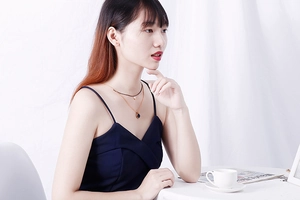 Detail of double-layer gold chain necklace with black pendants worn by a model