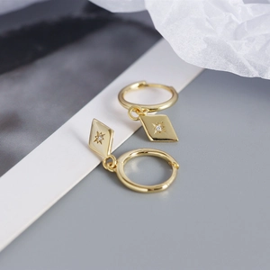 Detailed macro view of S925 sterling silver gold hoop earrings with star engraved rhombus charms