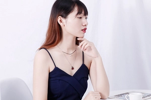 Close-up of double layer silver necklace with red gemstone and black beads on model