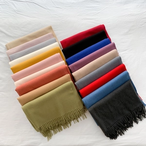 Close-up of neatly folded candy-colored scarves with fringe detail in multiple soft shades