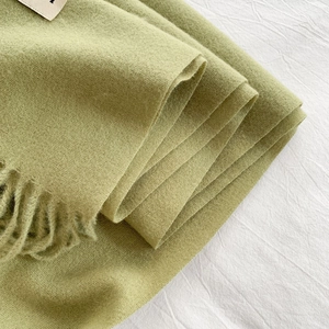 Close-up of light green cashmere-like scarf with fringe edges and soft texture