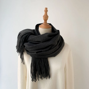 Detail shot of a dark grey knit cashmere-feel scarf with soft fringe edges and thick texture