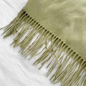 Detailed close-up of green cashmere-feel scarf showing soft tassels and knit texture