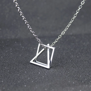 Close-up of geometric interlocking silver triangle and square pendant on a link chain