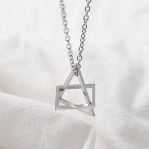 Minimalist silver geometric interlocking square and triangle pendant necklace on soft fabric