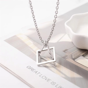 Detail of silver geometric triangle and square pendant necklace on a minimalist magazine