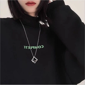 Close-up of geometric square silver pendant necklace on a black turtleneck sweater
