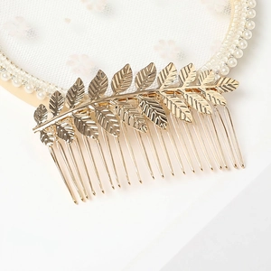 Detailed macro view of golden leaf alloy hair comb on elegant white lace background