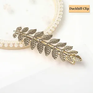 Detailed view of a golden alloy leaf-shaped hair clip with polished metallic finish