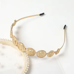 Close-up of golden headband with embossed vintage coins and black anti-slip ends