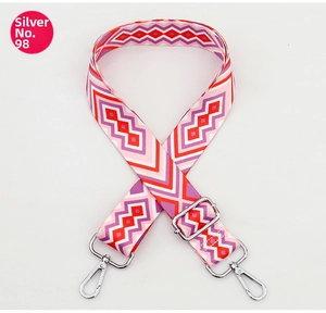 Detail of colorful geometric woven bag strap with silver metal hooks and buckle