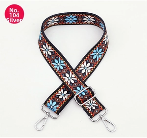 Close-up of wide embroidered strap with blue petals and adjustable silver buckle