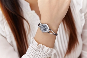 Close-up of women's silver bangle watch featuring black dial with rhinestone markers
