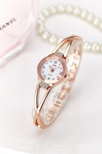 Detail of rose gold quartz watch with rhinestone accents and elegant hollow bracelet strap