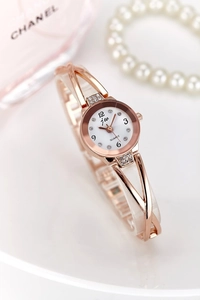 Close-up of rose gold hollowed bracelet watch with sparkling rhinestones and white dial